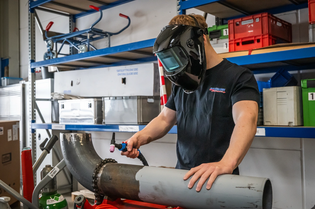 Ein Mitarbeiter schweißt ein Rohr in der Werkstatt