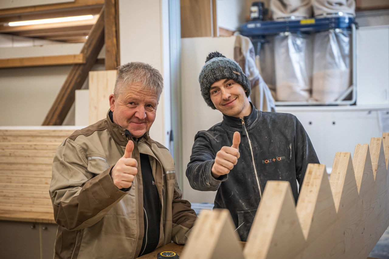 Zwei Tischler zeigen in der Werkstatt den Daumen nach oben