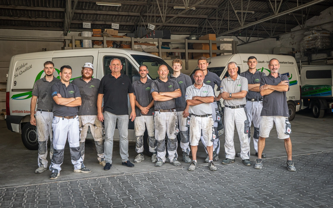 Malerteam in Arbeitskleidung vor den Firmenwagen in der Halle