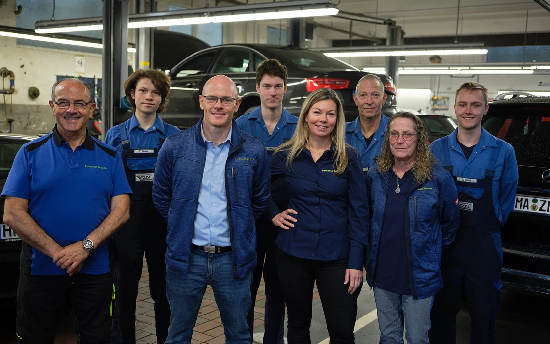 Werkstatt- und Serviceteam eines Autohauses zwischen den Hebebühnen