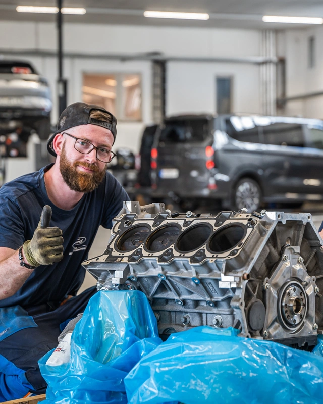 Zwei Mechatroniker von Autohaus Pfützenreuter mit einem ausgebauten Motor