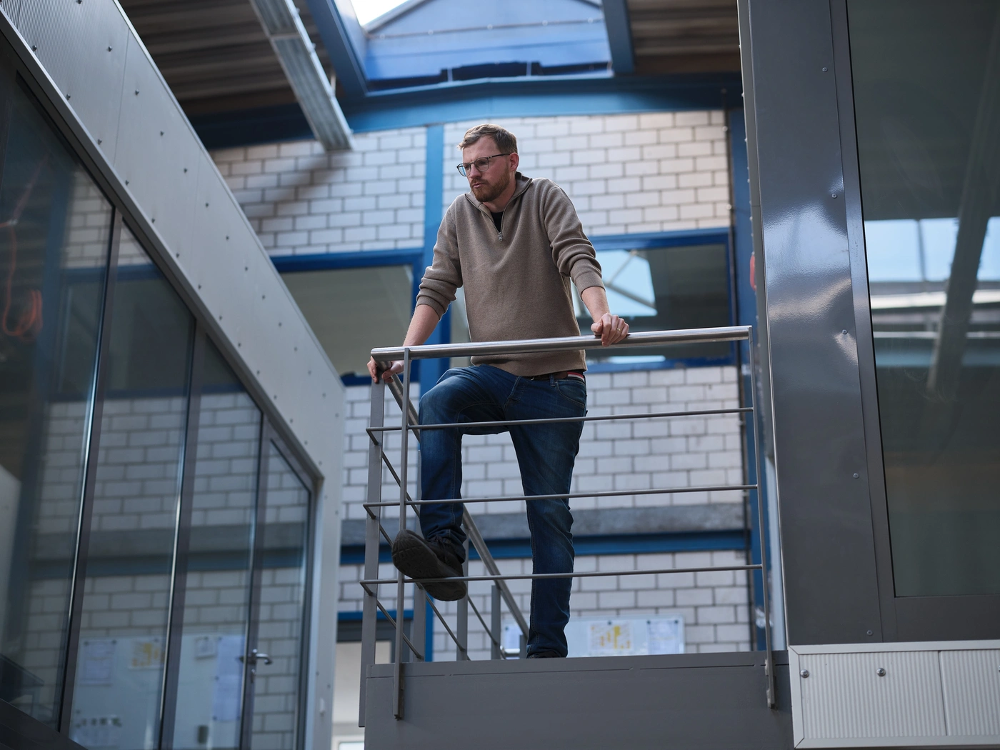 Führungskraft blickt von der Treppe über die Werkhalle