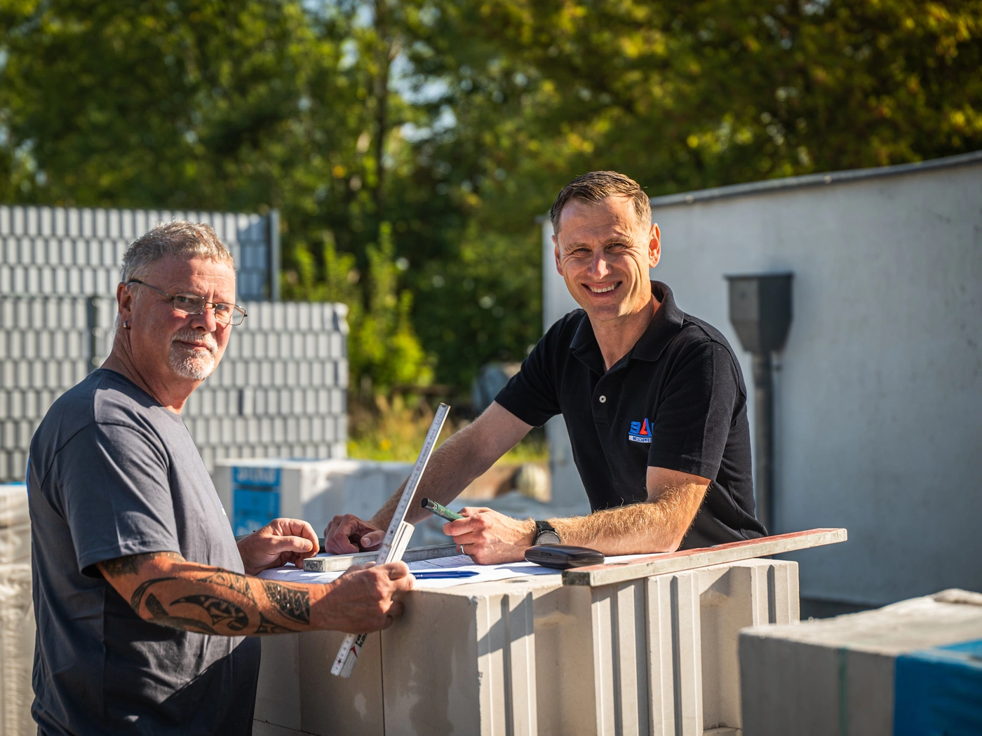 Zwei Kollegen besprechen einen Plan auf der Baustelle