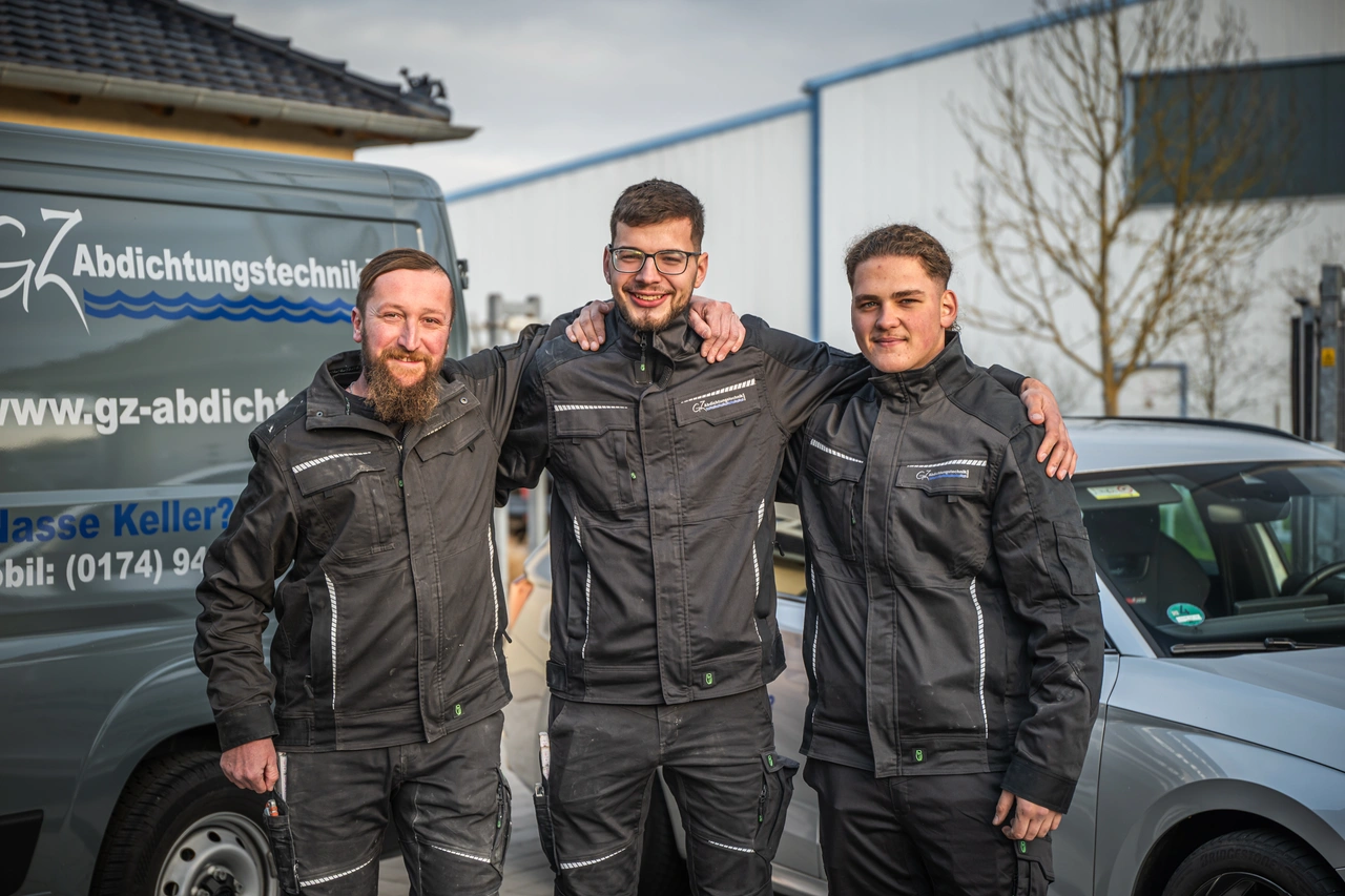 Drei Kollegen stehen vor einem Firmenwagen