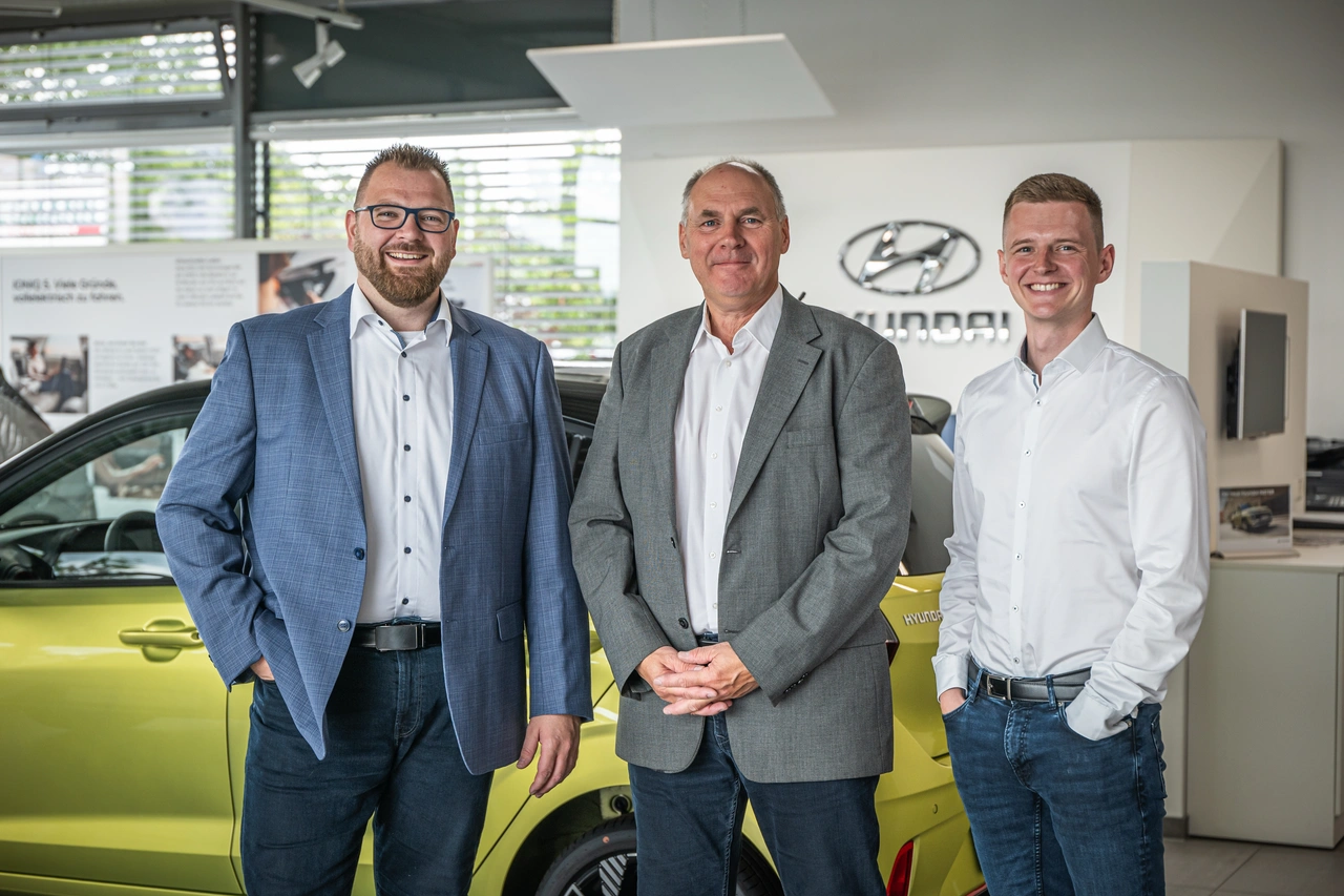 Drei Geschäftsführer stehen im Autohaus
