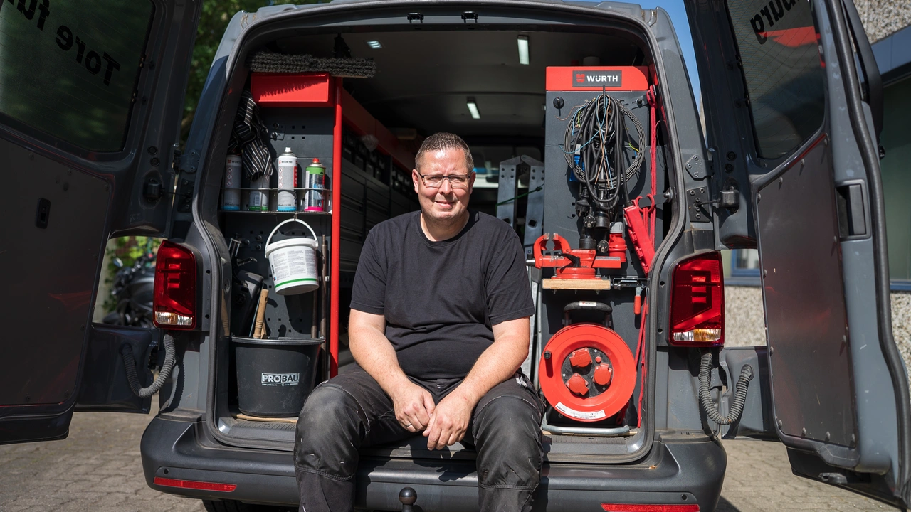 Ein Monteur sitzt auf der Ladekante seines Servicewagens