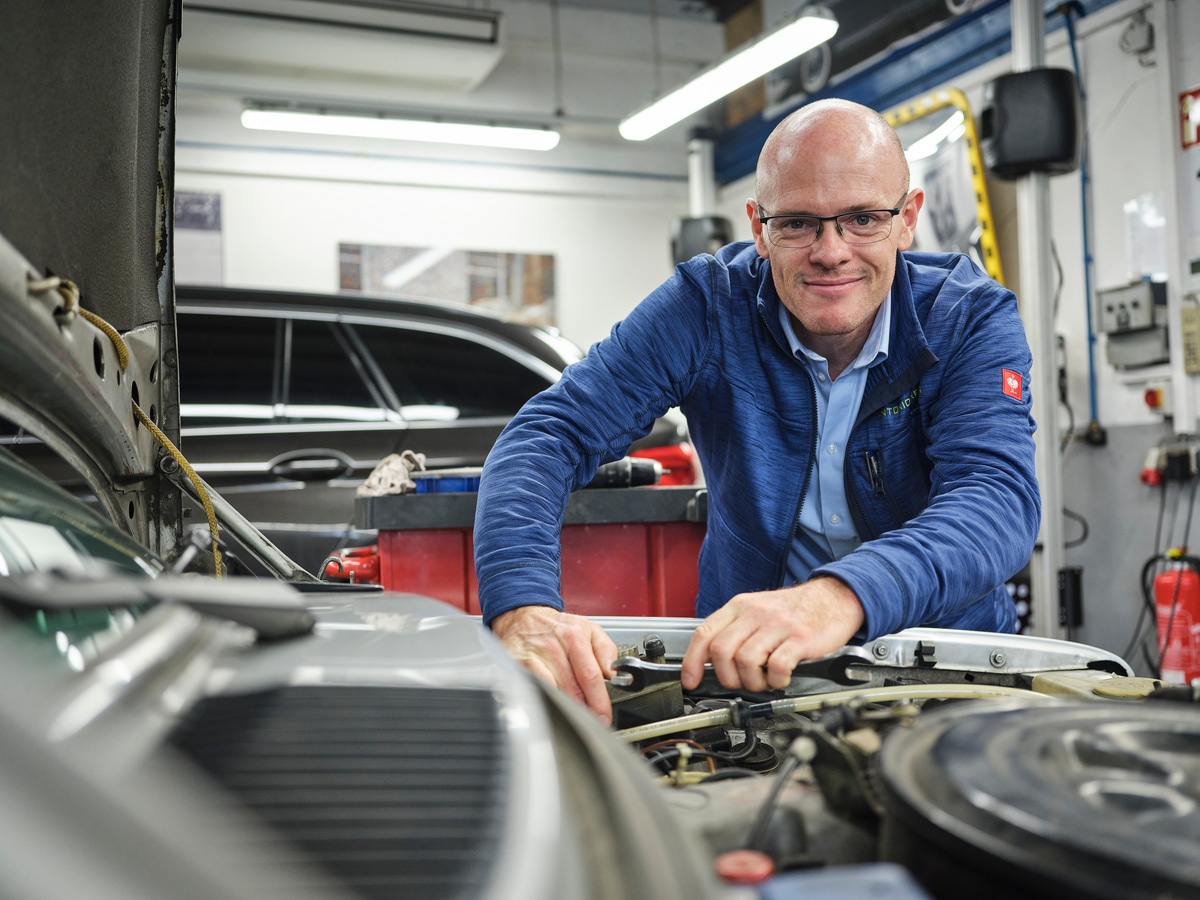 Kfz-Fachkraft arbeitet am geöffneten Motorraum